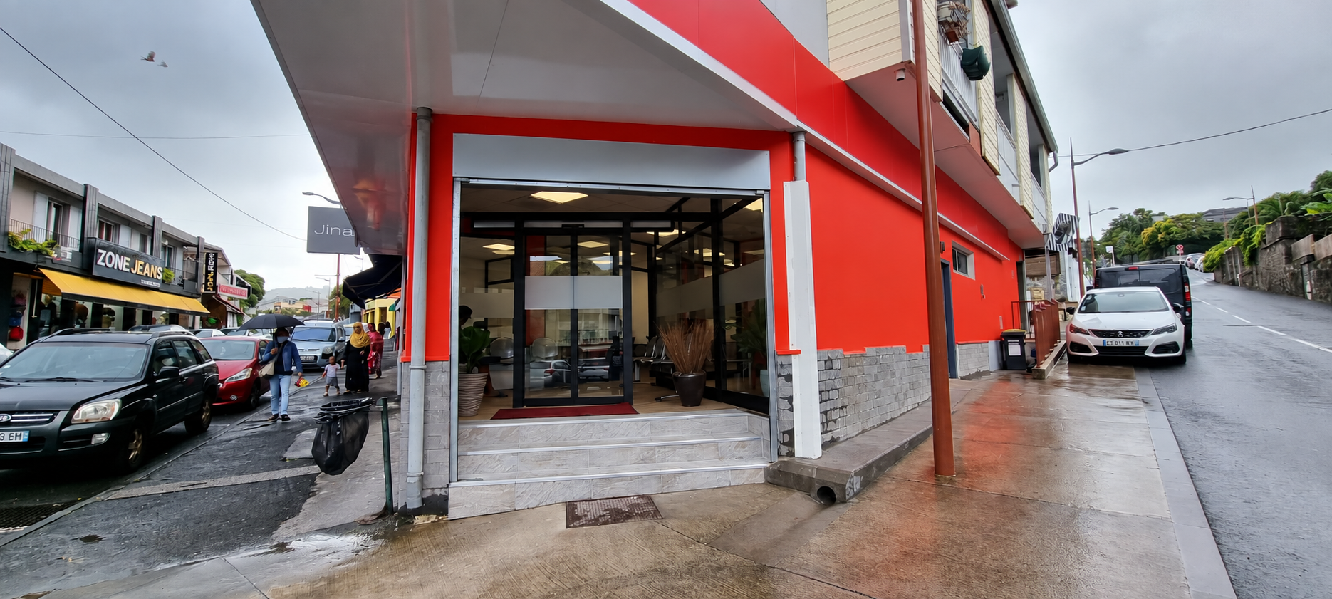 Façade du même local après rénovation, avec une peinture rouge et un soubassement gris.