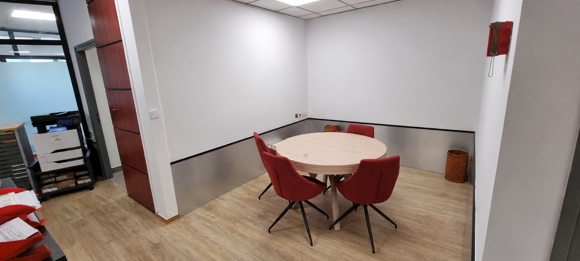 Intérieur rénové du local professionnel, avec un sol aspect bois, des murs blancs et gris et un plafond suspendu.
